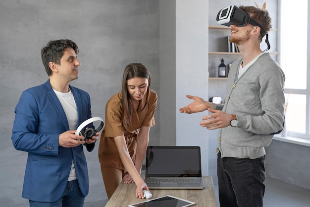 Joven equipo de profesionales que trabajan con portátil y casco de realidad virtual.