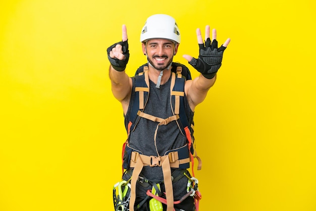 Joven escalador caucásico aislado de fondo amarillo contando seis con los dedos