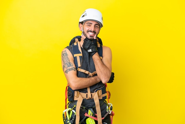 Joven escalador caucásico hombre aislado sobre fondo amarillo sonriendo