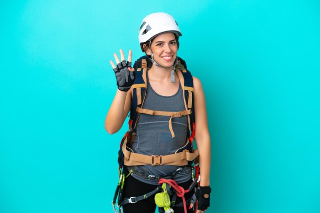 Joven escaladora italiana aislada de fondo azul feliz y contando cuatro con los dedos