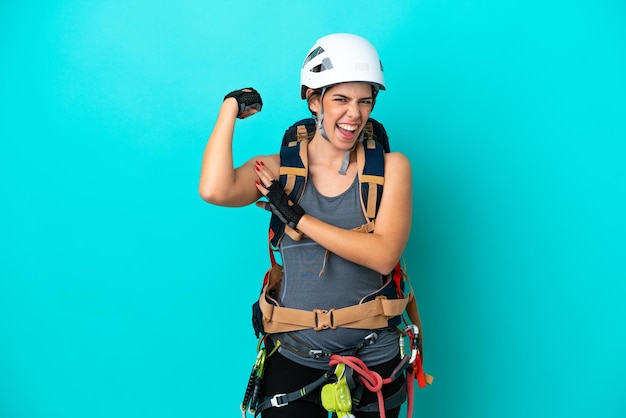 Una joven escaladora italiana aislada de fondo azul haciendo un gesto fuerte