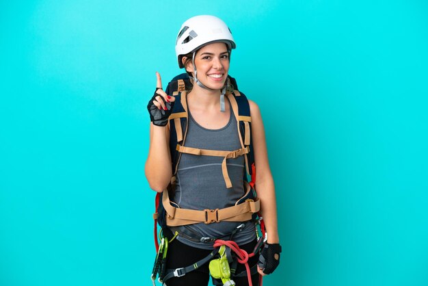 Joven escaladora italiana aislada de fondo azul mostrando y levantando un dedo en señal de lo mejor