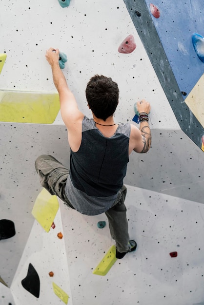 Joven escalando una pared en un muro de escalada interior