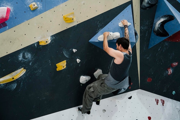 Joven escalando una pared en un muro de escalada interior