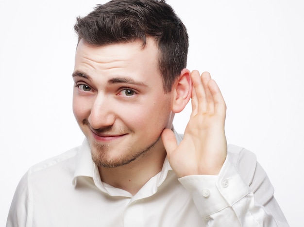 Joven escuchando algo sobre fondo blanco.