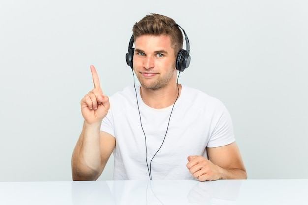 Joven escuchando música con auriculares mostrando el número uno con el dedo.