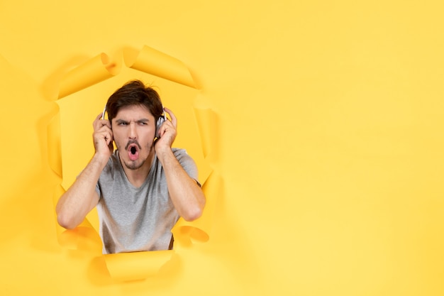 Joven escuchando música en auriculares sobre fondo amarillo sonido de ultrasonido de audio