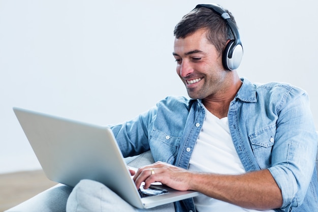 Joven escuchando música mientras usa la computadora portátil