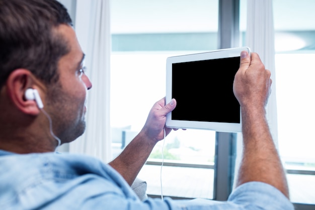 Joven escuchando música mientras usa la tableta