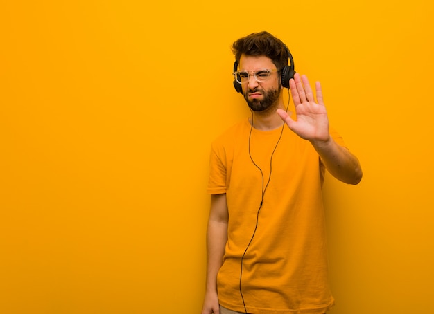 Joven escuchando música poniendo la mano delante