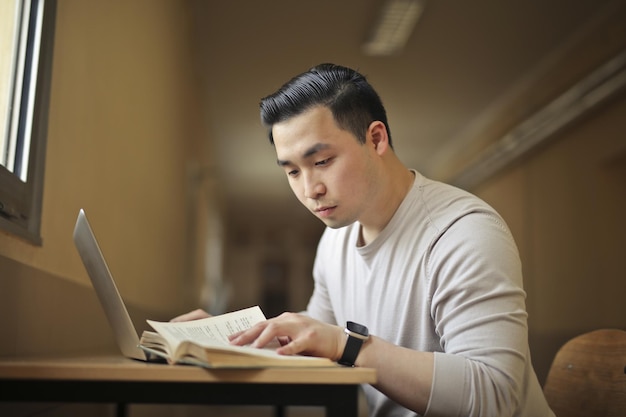 joven en la escuela estudiando con una laptop y un libro