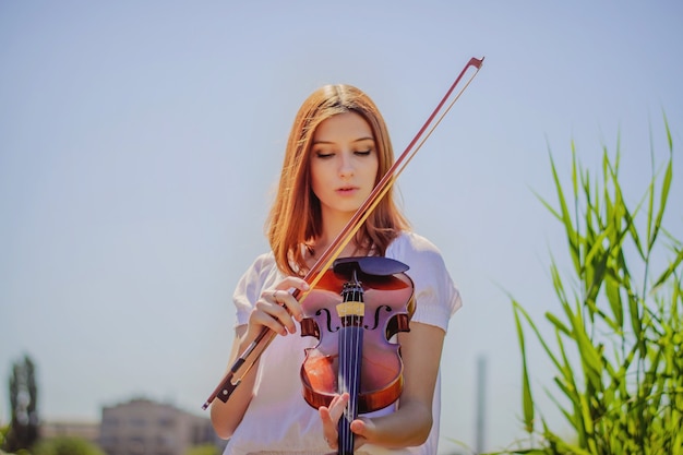 Joven eslava tocando el violín en la naturaleza