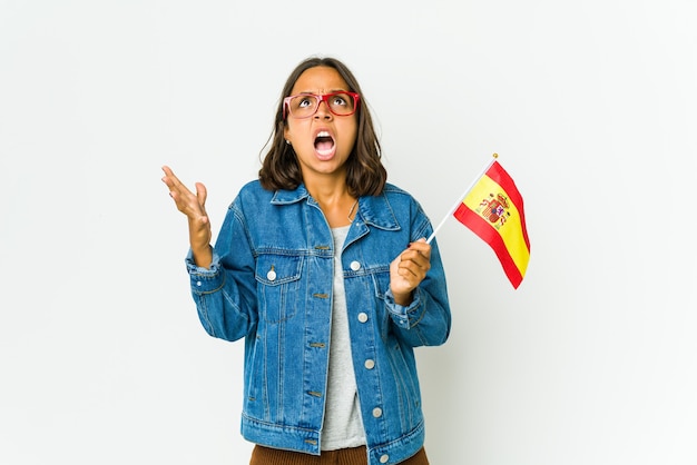 Joven española sosteniendo una bandera aislada en blanco gritando al cielo, mirando hacia arriba, frustrada.