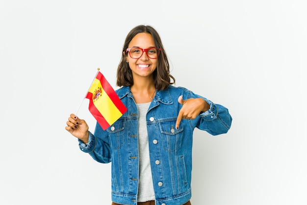 Foto joven española sosteniendo una bandera aislada en la pared blanca apunta hacia abajo con los dedos, sentimiento positivo