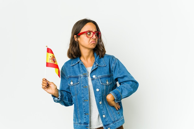 Joven española sosteniendo una bandera confundida, se siente dudosa e insegura.