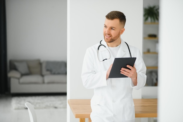 Joven especialista en cáncer masculino en bata de laboratorio usando tableta digital en la clínica