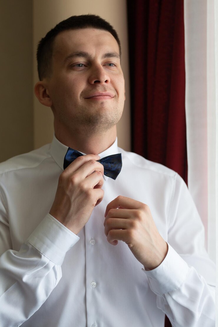 Un joven esposo va a una ceremonia de boda en un hotel de lujo con un traje azul y ajustando su pajarita mientras espera a la novia Amor e historia de amor durante las reuniones del novio