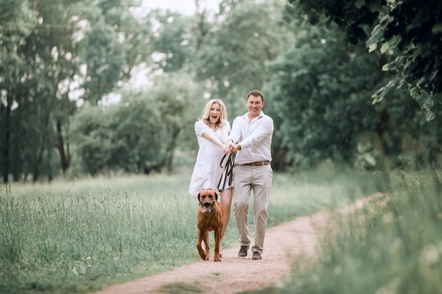 El joven esposo y su esposa se divierten con su perro mascota