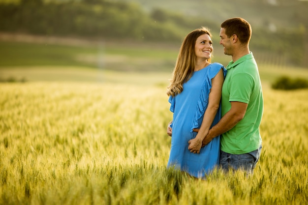 Joven esposo y su esposa embarazada en el campo de verano