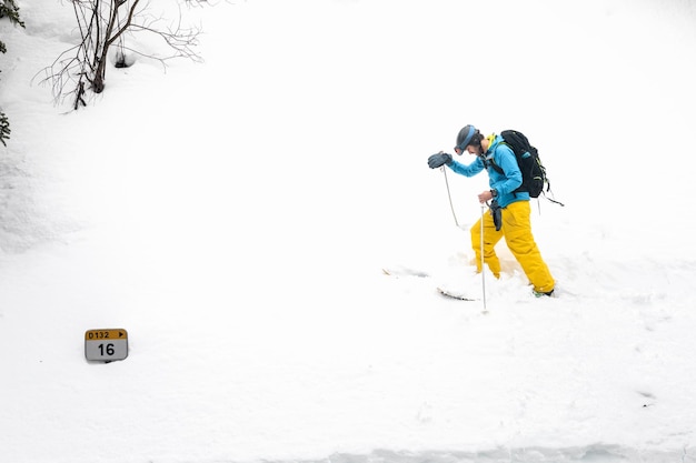 Joven esquiador caucásico caminando por una pared de nieve en los Pirineos.