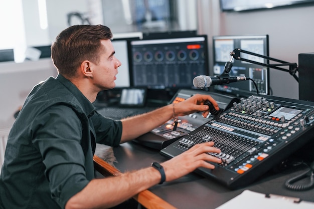 El joven está adentro en el estudio de radio está ocupado por transmisión