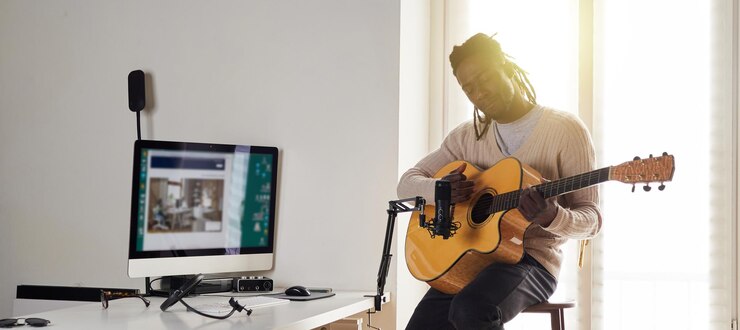 Foto el joven está cantando y tocando la guitarra mientras hace una grabación de audio en casa