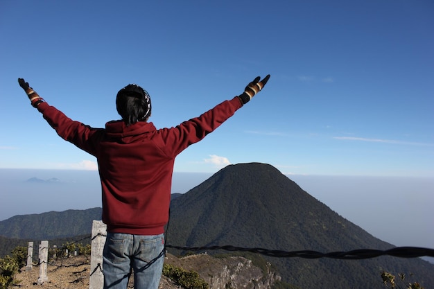 Un joven está en la cima de una montaña sintiendo libertad en el Monte Gede Pangrango, Java Occidental