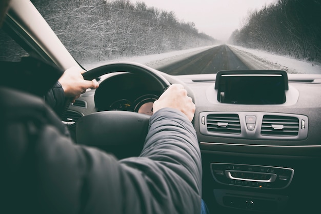 joven está conduciendo su automóvil a través de la carretera nevada sne