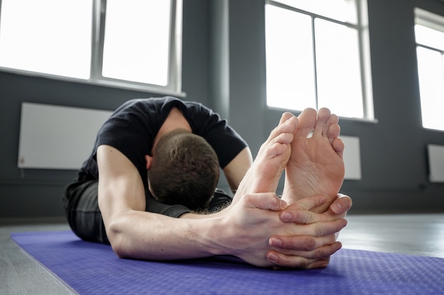 Joven está estirando en el gimnasio