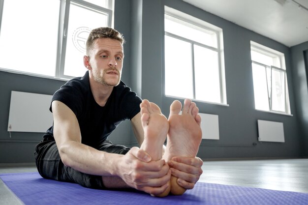 Joven está estirando en el gimnasio