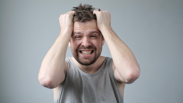 El joven está irritado, se está arrancando el pelo de la cabeza por el estrés