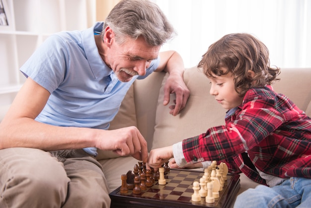 Joven está jugando al ajedrez con su abuelo en casa.