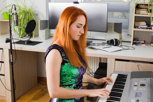 La joven está jugando en el estudio con un sintetizador.