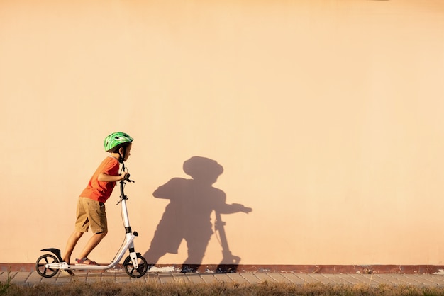 Un joven está montando un scooter en un casco protector