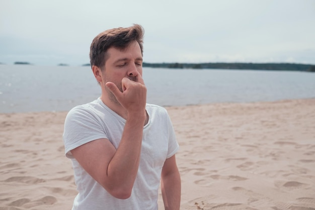 El joven está respirando pranayama sentado en la orilla del mar