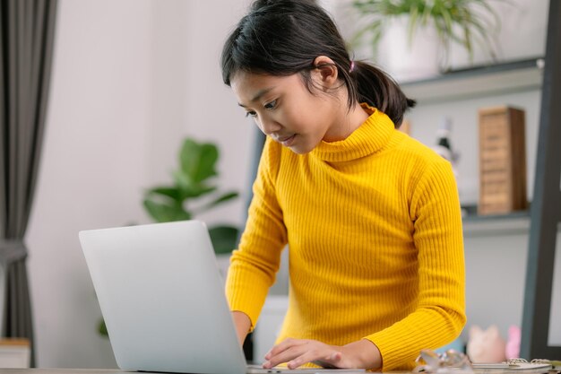 Una joven está sentada en un escritorio con una computadora portátil delante de ella