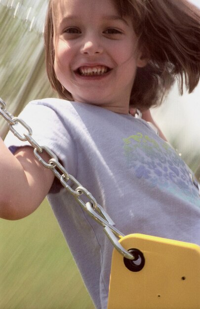 una joven está sonriendo mientras se balancea en un columpio