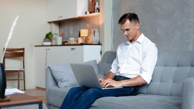 Joven está trabajando en una computadora portátil en su apartamento. vida domestica.