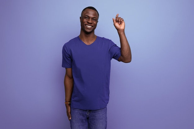 Un joven estadounidense guapo con una camiseta azul muestra su mano hacia el espacio.