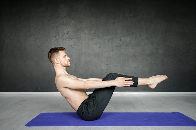 Foto joven está estirando en el gimnasio