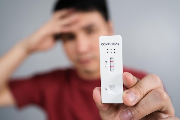 Joven estresado con resultado positivo de la prueba de coronavirus (Covid-19) con el kit de prueba rápida de antígeno (ATK)