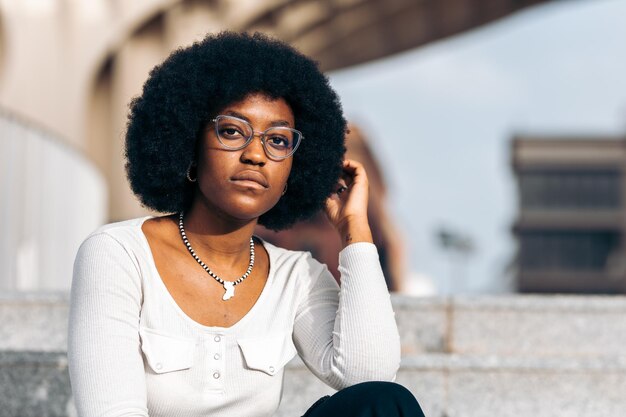 Joven estudiante adolescente negro de ensueño con gafas mirando a la cámara