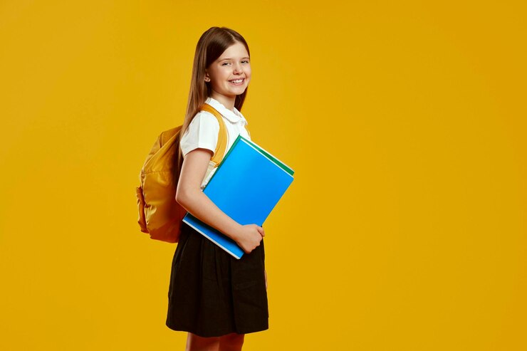 Un joven estudiante alegre con el cabello largo y una mochila sostiene con confianza cuadernos de colores de pie