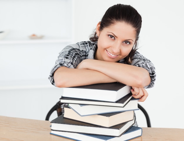 Joven estudiante apoyándose en libros