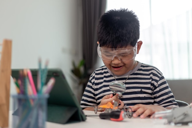 Joven estudiante de asia aprende de forma remota en línea en casa codificando un automóvil robot y un cable de placa electrónica en STEM STEAM ingeniero matemático ciencia tecnología código informático en robótica para niños