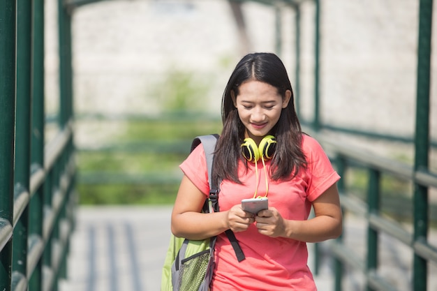 Joven estudiante asiática en su actividad al aire libre, caminando mientras mira