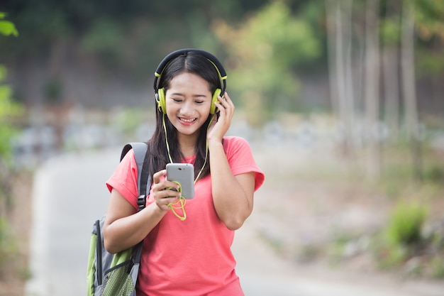 Joven estudiante asiática en su actividad al aire libre, escuchando el mu