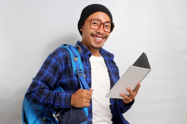 Un joven estudiante asiático feliz parece emocionado mientras sostiene un libro