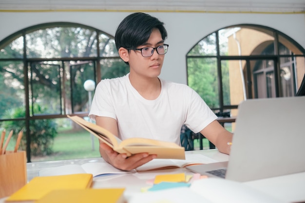 Joven estudiante asiático se prepara para leer libros para exámenes en la universidad