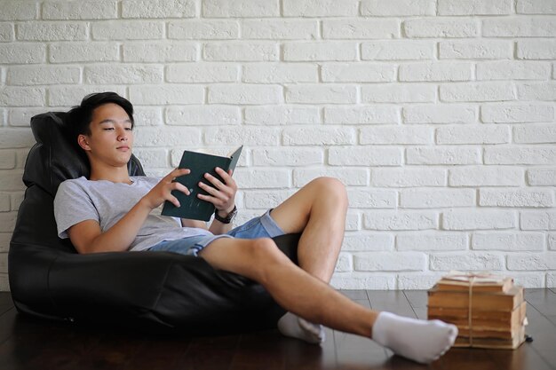 Joven estudiante asiático sentado en la almohada y preparándose para el examen